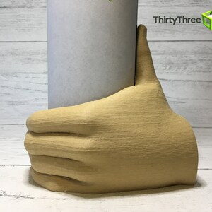May include: A beige 3D printed hand holding a white cylinder. The hand is giving a thumbs up.