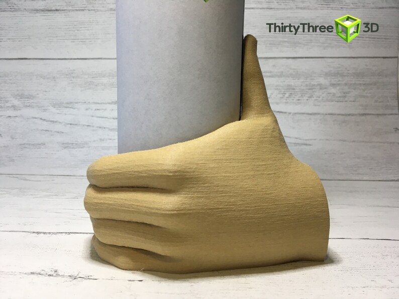 May include: A beige 3D printed hand holding a white cylinder. The hand is giving a thumbs up.