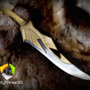 May include: A gold and silver decorative dagger with a wing design. The dagger is lying on a brown fur surface.
