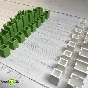 May include: Two sets of green and white plastic building blocks. The green blocks are arranged in a staggered pattern, while the white blocks are arranged in a straight line.