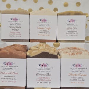 May include: Six rectangular goat milk soap bars arranged in two rows. Each bar features a white paper label with the Naturally Enchanted Soapworks logo, scent name, and a net weight of 4 oz (113 g). Scents include Warm Vanilla & Musk, Pumpkin Souffle, Apple Pie, Butterscotch Brulee, Cinnamon Bun, and Pumpkin Espresso.