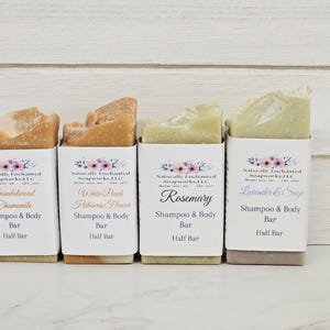 K&ouml;nnte beinhalten: Vier halbe Shampoo- und K&ouml;rperseifen in wei&szlig;er Papierverpackung. Die Seifen sind mit den D&uuml;ften Sandelholz Kamille, White Peach Hibiscus Flower, Rosmarin und Lavendel & Salbei beschriftet. Die Verpackung hat ein Blumenmuster.