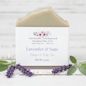K&ouml;nnte beinhalten: Ein hellgr&uuml;nes Shampoo- und K&ouml;rperseifenst&uuml;ck mit dem Text "Lavender & Sage" und "Net Wt. 4.5 oz." Die Seife wird mit Zweigen von Lavendel und Salbei pr&auml;sentiert. Das Produkt stammt von Naturally Enchanted Soapworks, LLC.