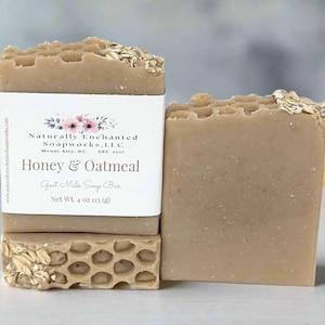 May include: A light brown Honey & Oatmeal goat milk soap bar with a honeycomb texture on top and embedded oats. The label reads Naturally Enchanted Soapworks, LLC, Honey & Oatmeal, Goat Milk Soap Bar, Net Wt. 4 oz 113 (g).