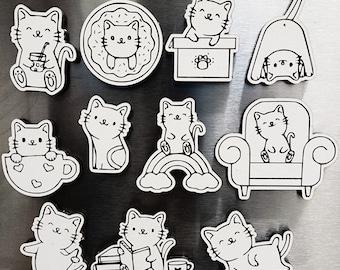 May include: Set of 10 black and white cat magnets with various poses and activities, including a cat drinking from a cup, a cat sitting on a donut, a cat sitting on a rainbow, a cat sitting in a chair, a cat reading a book, and a cat sleeping.