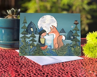 May include: A greeting card featuring a girl with a crown and a fox looking at each other under a full moon. The scene is set in a forest with trees, mountains, and fireflies.