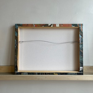 Pu&ograve; includere: Il retro di una stampa su tela incorniciata con un design astratto colorato. La cornice &egrave; in legno e ha una finitura marrone scuro. La tela &egrave; tesa sul telaio ed &egrave; fissata con punti metallici. La stampa &egrave; protetta da una vernice trasparente.