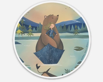 May include: A round sticker featuring an illustration of a girl hugging a brown bear in a boat on a lake. The bear and girl are in the center, with mountains and trees in the background. The sticker has a white border.