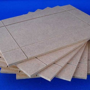 May include: A stack of six beige, rectangular pieces of wood with a grid pattern. The wood is unfinished and has a rough texture.