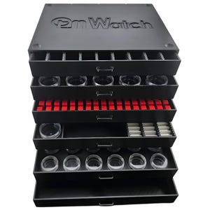 May include: A black watch storage box with multiple pull-out drawers. The top of the box has the embossed text "pm Watch". The drawers contain watch parts and clear containers. Some drawers have red and white inserts.