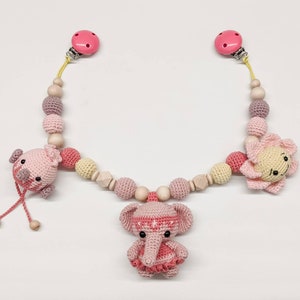 May include: A pink and yellow crocheted baby toy with a wooden bead chain and clips. The toy features a crocheted elephant, a crocheted flower, and a crocheted bird.
