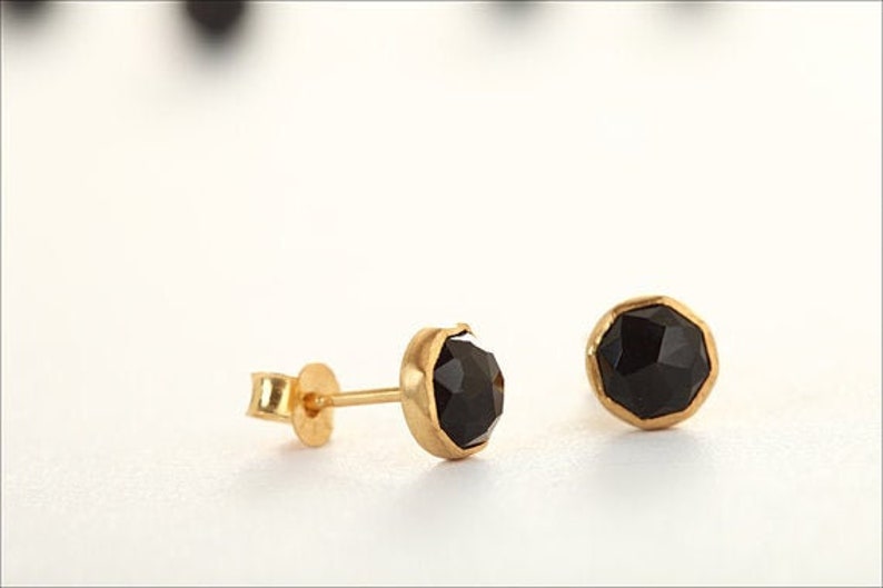 May include: A pair of gold stud earrings with black faceted gemstones.
