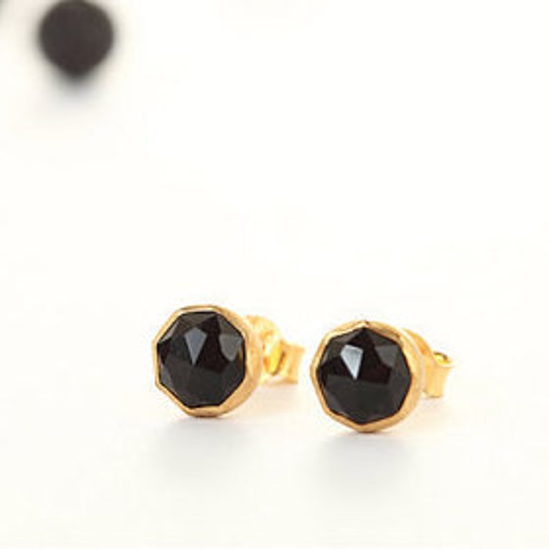 May include: A pair of gold-toned stud earrings with black faceted gemstones.