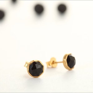 May include: A pair of gold stud earrings with black gemstone accents.