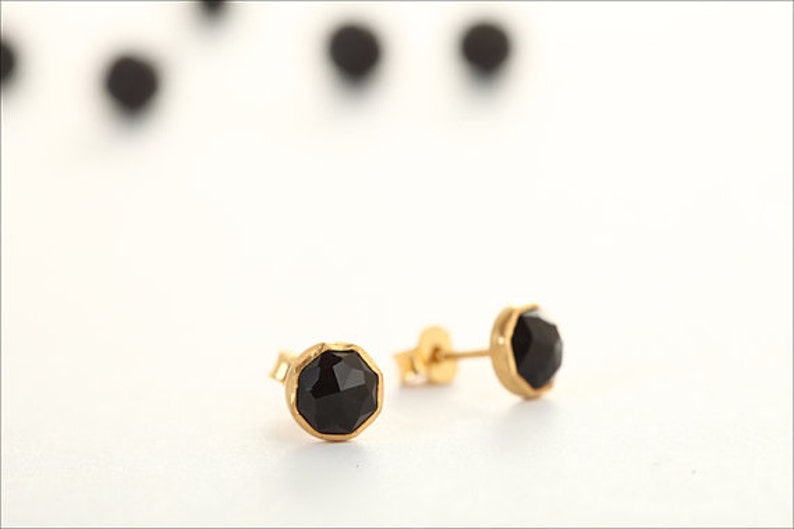 May include: A pair of gold stud earrings with black gemstone accents.
