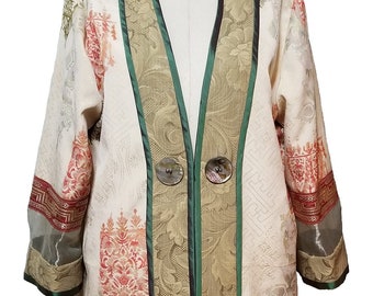 May include: A long, cream-colored jacket with a green and gold trim. The jacket has a floral pattern and two large, round buttons.