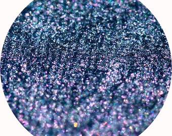 May include: Close-up of a blue glitter with iridescent shimmer. The glitter has a gradient effect, with a darker blue at the top and a lighter blue at the bottom.
