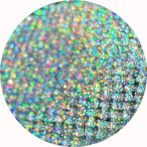 Puede incluir: Imagen circular con una superficie brillante e iridiscente. La superficie está cubierta de pequeñas formas circulares y coloridas que reflejan la luz, creando un efecto brillante. Los colores incluyen tonos de verde, azul y rosa.