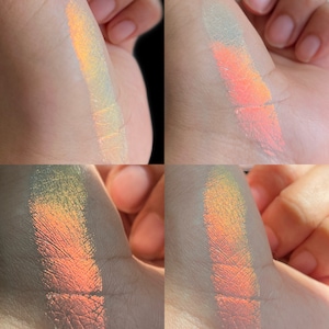 Puede incluir: Cuatro muestras de maquillaje iridiscente en una mano. Los colores cambian de amarillo a naranja y rosa, creando un efecto brillante. El maquillaje parece tener un acabado metálico o nacarado.