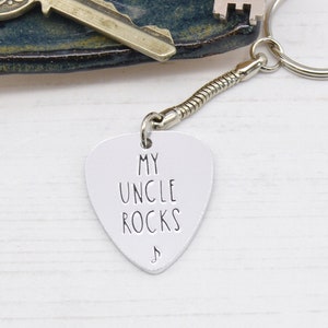 May include: A silver guitar pick keychain with the text "My Uncle Rocks" and a musical note symbol.