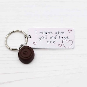 May include: A white metal keychain with a brown chocolate charm and the text "I might give you my last one" with small red hearts.
