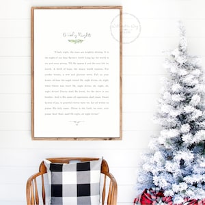 May include: A rectangular wooden framed wall sign featuring the lyrics to O Holy Night in black text on a white background, with a small green sprig illustration above the title and a decorative flourish at the bottom of the printed text.