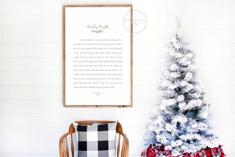 May include: A rectangular wooden framed wall sign featuring the lyrics to O Holy Night in black text on a white background, with a small green sprig illustration above the title and a decorative flourish at the bottom of the printed text.