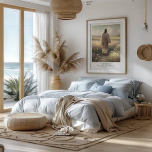 Puede incluir: Un dormitorio sereno con una cama grande cubierta con ropa de cama y almohadas de color azul claro. Una obra de arte enmarcada cuelga sobre la cama, y una alfombra y un otom&aacute;n tejidos est&aacute;n en el suelo. Una gran ventana ofrece una vista del oc&eacute;ano.