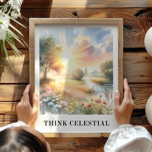 May include: A framed art print featuring a vibrant landscape painting with a bright sunburst, a river, and colorful flowers. The text "THINK CELESTIAL" is printed at the bottom. The artwork is held by a person.