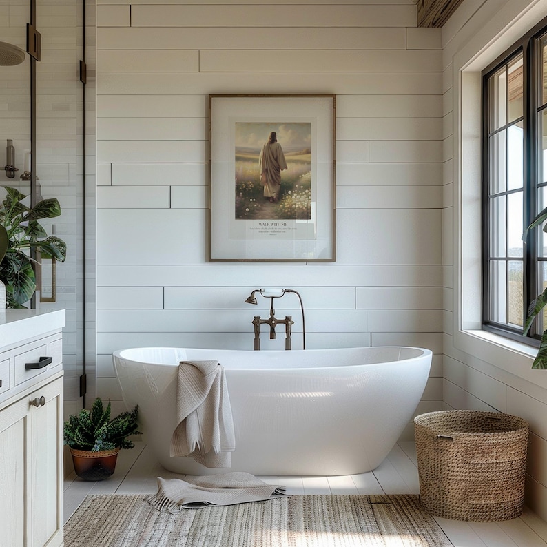 Puede incluir: Un ba&ntilde;o moderno con una ba&ntilde;era blanca exenta, un cuadro enmarcado y una cesta de mimbre. Las paredes son de tablones blancos y una ventana proporciona luz natural. Una toalla beige cuelga de la ba&ntilde;era.