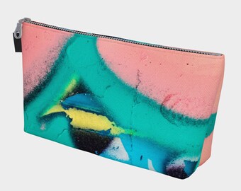 Puede incluir: Una bolsa de cremallera rosa y turquesa con un diseño abstracto colorido. El diseño presenta salpicaduras de pintura azul, amarilla y negra.