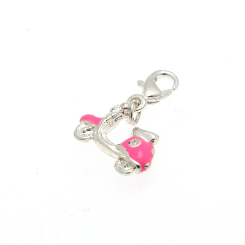May include: A silver charm in the shape of a pink scooter with white polka dots. The charm has a silver lobster clasp.