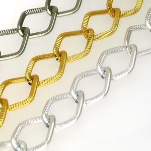 Chaîne losange en aluminium anodisé, couleurs argent, or et noir, taille 18 x 13 mm. Vendu au mètre.