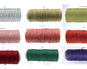 May include: A collection of colorful twine spools in various shades, including silver, gold, lime green, pink, red, green, orange, and purple. Each spool is labeled with its color name, offering a diverse range of options for crafting and decorative projects.