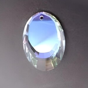 Puede incluir: Un prisma de cristal de vidrio transparente con un agujero en la parte superior para colgar. El prisma tiene un dise&ntilde;o facetado y refleja la luz.