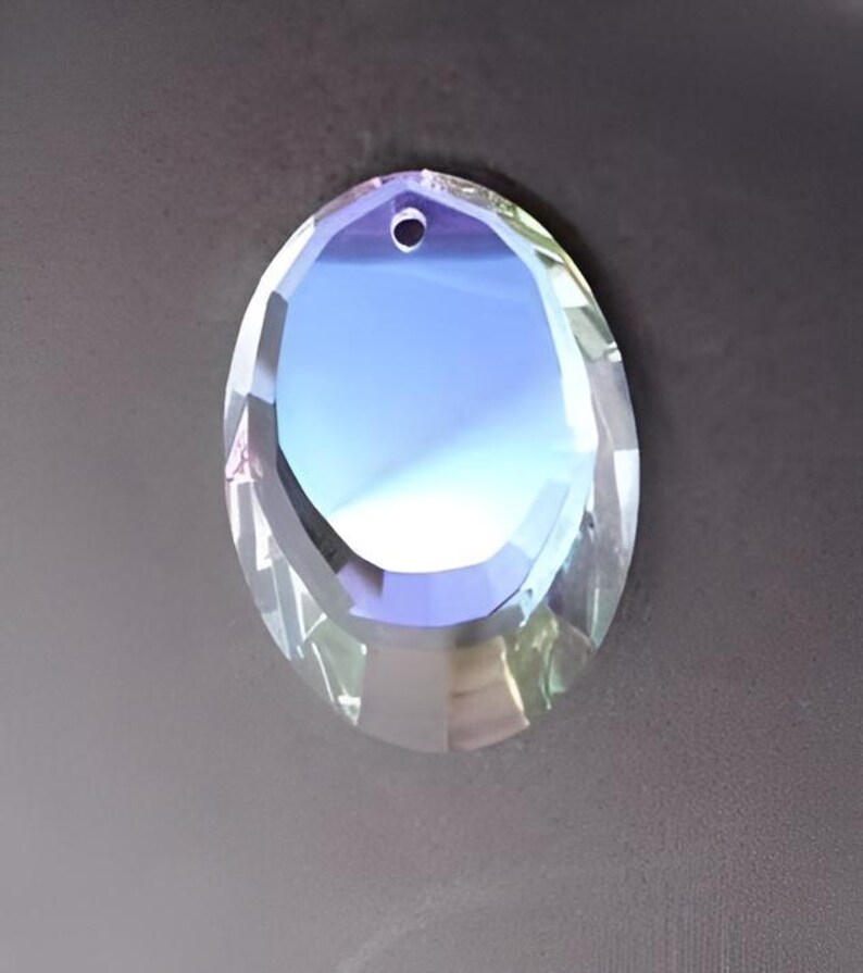 Puede incluir: Un prisma de cristal de vidrio transparente con un agujero en la parte superior para colgar. El prisma tiene un dise&ntilde;o facetado y refleja la luz.