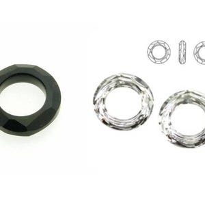 May include: Two clear crystal rings and one black faceted ring. The rings are all round and have a hole in the center. The rings are about 1 inch in diameter.
