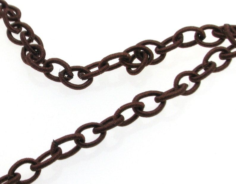 May include: Brown elastic chain with oval links. The chain is made of a soft, flexible material and is perfect for adding a touch of style to any project.