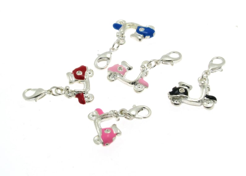 May include: Five silver charm pendants shaped like scooters with different colored paint jobs. The scooters have a silver clasp on the back. The colors are red, pink, blue, black, and pink.