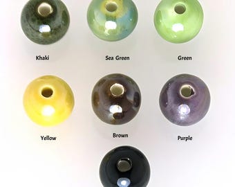 Puede incluir: Siete cuentas de cerámica en varios colores, incluyendo caqui, verde mar, verde, amarillo, marrón, morado y negro. Las cuentas son redondas y tienen un agujero en el centro.