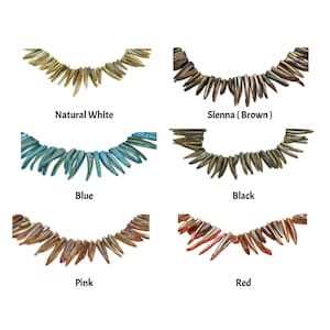 Puede incluir: Seis hebras de cuentas de concha iridiscente en diferentes colores: blanco natural, siena (marrón), azul, negro, rosa y rojo. Cada hebra está dispuesta en forma de semicírculo, con las cuentas apuntando hacia arriba.