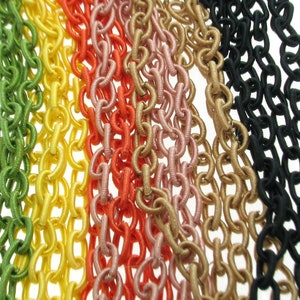 May include: A close-up of seven different colored chains made of fabric. The chains are green, yellow, orange, pink, gold, beige, and black.