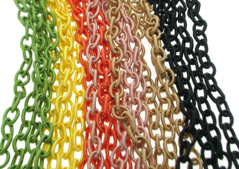 May include: A close-up of seven different colored chains made of fabric. The chains are green, yellow, orange, pink, gold, beige, and black.