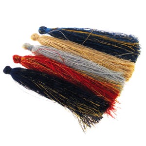 May include: Five colorful tassels with gold thread accents. The tassels are in shades of blue, beige, gray, red, and black.