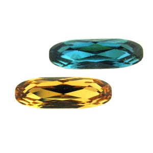 May include: Two oval-shaped gemstones, one blue and one gold, with a faceted cut.