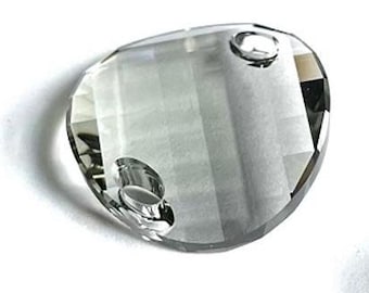 Può includere: Un prisma di cristallo di vetro trasparente con due fori. Il prisma ha la forma di una lacrima e una superficie sfaccettata.