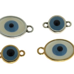 Könnte beinhalten: Vier böse Augen-Anhänger mit silbernen und goldenen Einstellungen. Zwei Anhänger sind oval geformt mit weißem und blauem Emaille. Zwei Anhänger sind rund mit blauem Emaille.