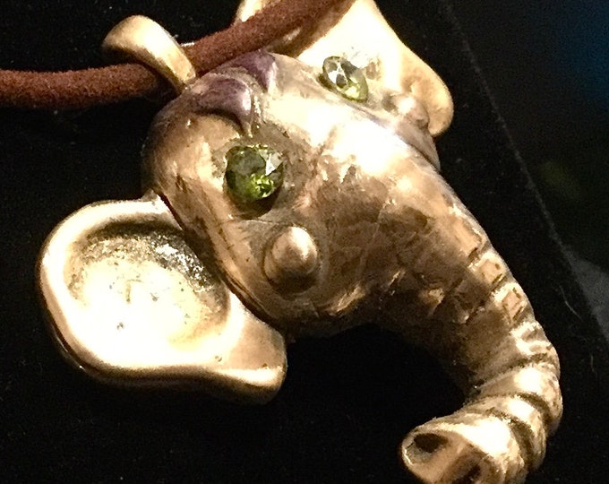 CF013  Elephant Head made of rose bronze with cubic zirconia eyes, on a heavy weight brown cord. It’s good luck when a trunk is turned up