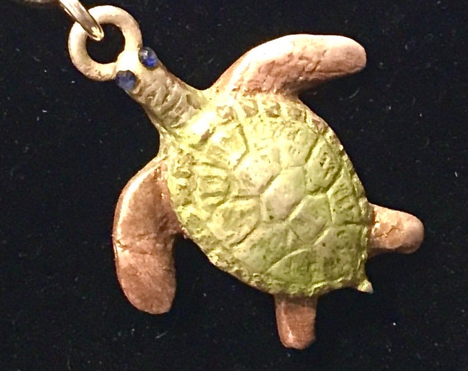 CF092.  Pure silver turtle enhanced with jewelers dye and sapphires for eyes,  cord is suede and 18”, silve content is .999