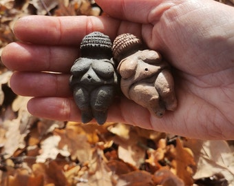 Peut inclure: Deux petites figurines en céramique de femmes, l'une est noire et l'autre est brune. Les deux portent des chapeaux et ont un ventre rond.